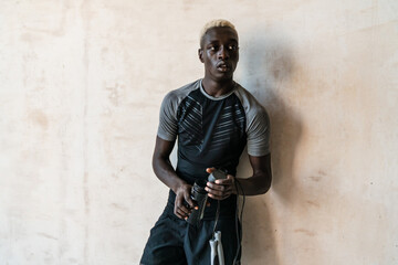 Young african american man holding jumping rope and water indoors