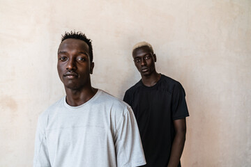 Two young handsome african american men standing over wall indoors