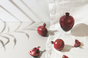 Pomegranates with a vase in light on pastel background.