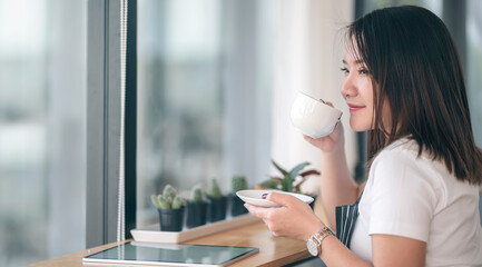 Portrait of young beautiful asian woman drinking coffee with happiness while sitting at modern cafe.