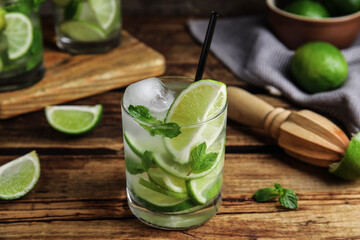 Delicious mojito and ingredients on wooden table