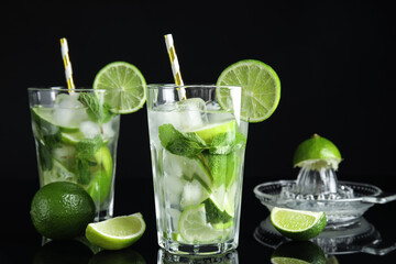 Delicious mojito and ingredients on black background