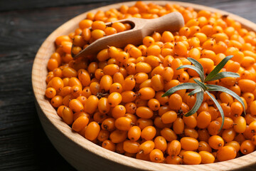 Ripe sea buckthorn berries on black wooden table, closeup