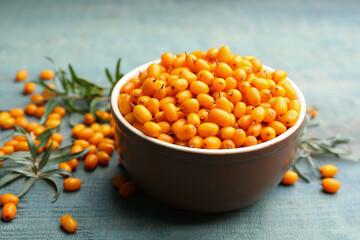 Ripe sea buckthorn berries on blue wooden table, closeup