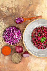 top view beetroot salad on the basis of red onions chopped cabbage turmeric and ground pepper in a gray ceramic plate on a wooden background with copy space
