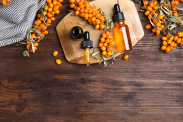 Flat lay composition with sea buckthorn oil on wooden table. Space for text