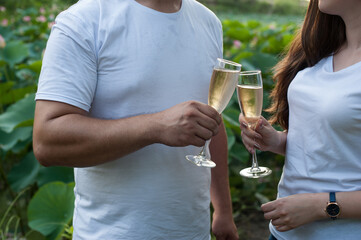 couple in white T-shirts with champagne glasses on the background of lotus lake