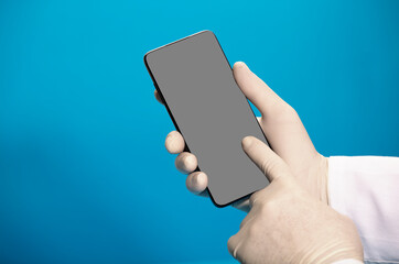phone in the hands of a doctor (telephone assistance) with surgical glove and blue background