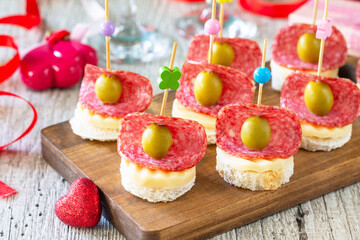 Valentines day or birthday romantic snacks close-up. Canapes with bread, cheese, salami and olives.
