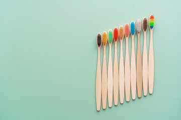A set of Eco-friendly antibacterial toothbrushes made of bamboo wood on a light green background. Environmental care trends