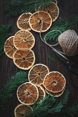 Fototapeta na wymiar Making Christmas garland from dried oranges. Top down view, flatlay