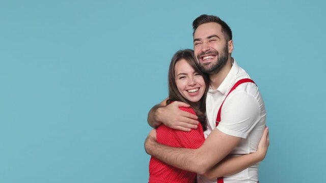 Excited cheerful young couple friends man woman 20s wearing white red clothes posing isolated on blue color background in studio. People sincere emotions lifestyle concept. Meeting greeting hugging