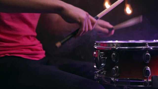 Man playing on snare drum with drumsticks. Closeup.