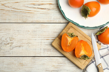 Tasty ripe persimmons on white wooden table, flat lay. Space for text