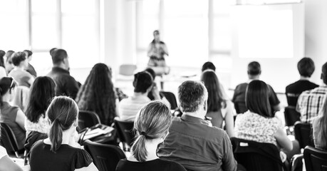 Business and entrepreneurship symposium. Female speaker giving a talk at business meeting. Audience...