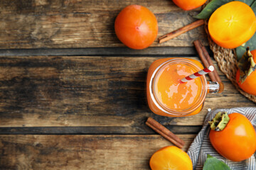 Tasty persimmon smoothie and fresh fruits on wooden table, flat lay. Space for text