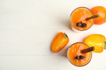 Tasty persimmon smoothie with anise and cinnamon on white wooden table, flat lay. Space for text