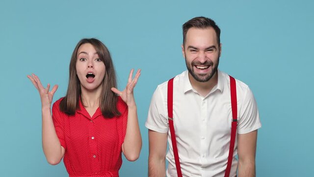 Funny crazy loony young couple friends man woman in white red clothes isolated on blue background . People lifestyle concept. Point fingers on blowing puffing cheeks with funny face crazy expression