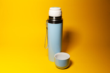Close-up of blue thermos on yellow background.