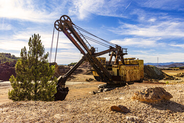 Old rusty bulldozer in Ríotinto's open pit mines with blue sky and clouds.