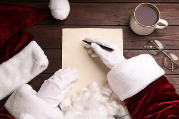 Top view of Santa writing letter at wooden table, closeup