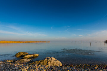 rocks and gravel on the shore from a frozen lake with sky