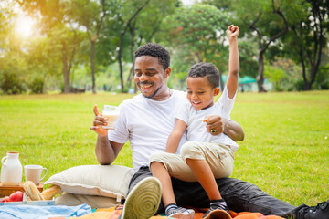 Cheerful african american father and son having a picnic in the park, Happiness family concepts