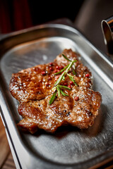 Beef steak garnished with rosemary lies on an steel plate