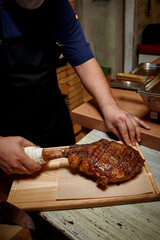 A chef in a restaurant cooking Tomahawk steak on a beef bone. Close-up of hands