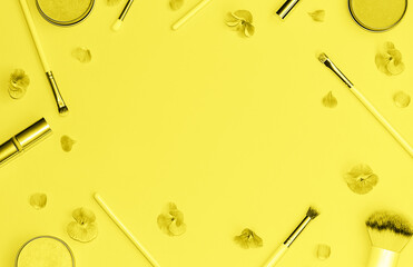 Flat lay composition with decorative makeup products and flowers toned in trendy yellow color. Flat lay style. Color 2021 concept.