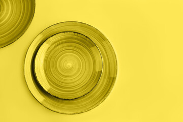 Abstract trendy yellow background with beautiful ceramic plates. Backdrop for your design. Flat lay style. Color 2021 concept.