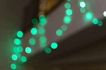 Abstract green bokeh background of blurred lights garlands on dark gray background, for Christmas, New Year and holidays