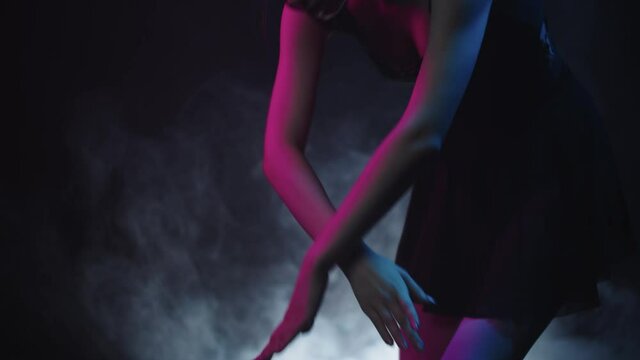 Young woman ballerina in black studio dancing in neon lighting