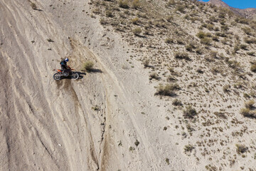 Extreme Rider climbing sand mountain on off-road cross enduro motorcycle