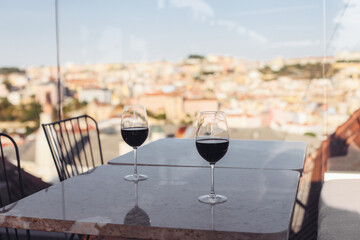 Obraz premium Two glasses of red wine on a rooftop terrace, with a European city view, sunset light