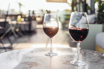 Two glasses of red wine on a rooftop terrace, sunset light 