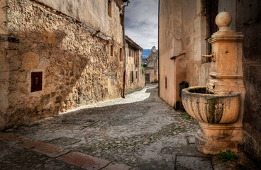 Fototapeta na wymiar Bonita imagen en la que se ve en primer plano una fuente en la villa medieval de Pedraza ( Segovia ) España.