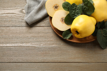 Fresh ripe organic quinces with leaves on wooden table, above view. Space for text