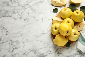 Naklejka na ściany i meble Fresh ripe organic quinces with leaves on white marble table, flat lay. Space for text