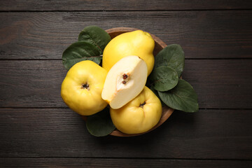 Fresh ripe organic quinces with leaves on wooden table, top view