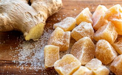 Close up of home made ginger candies and fresh ginger with sugar on wooden table. 
