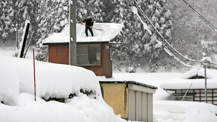 大雪に見舞われた町で雪下ろしをする人（豪雪地帯のイメージ） © tokyo studio