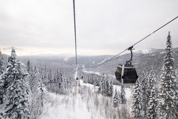 Gondola lift in the ski resort on snow covered slop, winter trees, mountains landscape