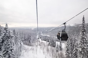 Fensteraufkleber Gondola lift in the ski resort on snow covered slop, winter trees, mountains landscape © Annatamila
