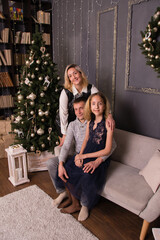 Naklejka premium Happy beautiful family in a Christmas interior of an apartment or house, near an elegant Christmas tree