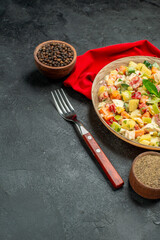 side close view of bowl of vegetable salad with pepper red napkin and fork on side with free place for text on dark grey background