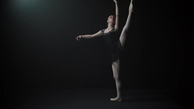 Young graceful woman ballerina in black dress slowly dancing on her tiptoes