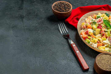 side close view of veggie salad on red napkin with fork notepad and pepper on side and free place for your text on dark grey background