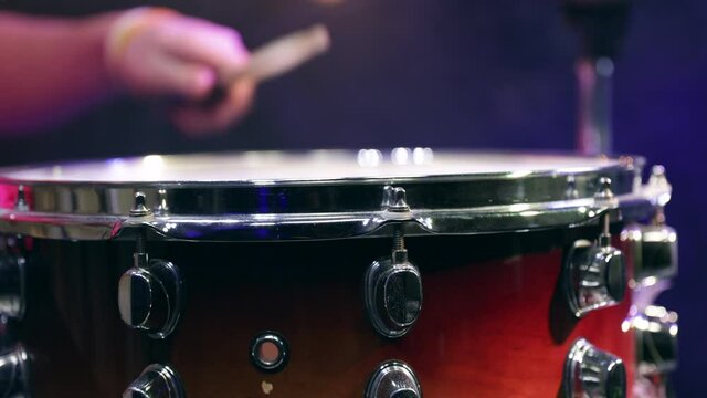 Man playing on snare drum with drumsticks. Closeup.