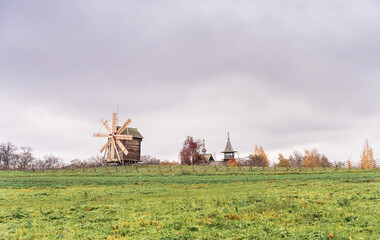 Fototapeta na wymiar Historic site of wooden church and windmill of Kizhi Island, Republic of Karelia, Russia. Moody autumn landscape.